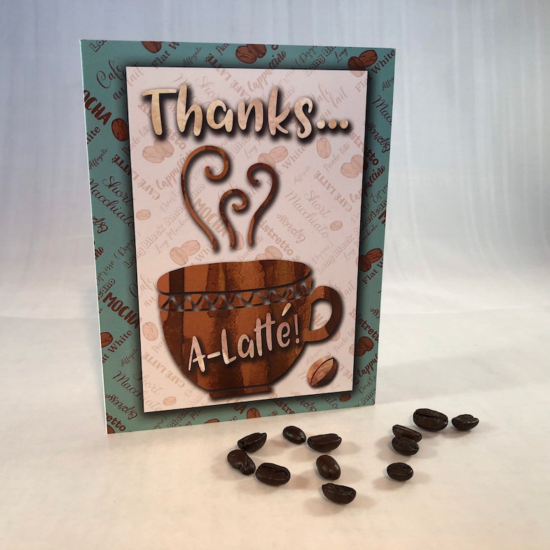 以下が含まれることがあります： ハート型の蒸気を立てた茶色のコーヒーカップが描かれた、ありがとうカード。カードは薄い青色の背景にコーヒー豆の模様が描かれており、「ありがとう&hellip; A-Latte!」という文字が書かれています。