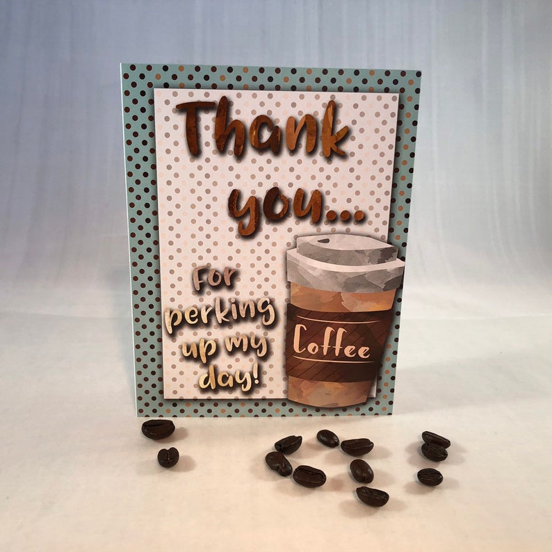 以下が含まれることがあります： 茶色の水玉模様の背景と茶色のコーヒーカップのイラストが描かれたサンキューカード。カードには「ありがとう...一日を元気にさせてくれて！」とカップには「コーヒー」と書かれている。