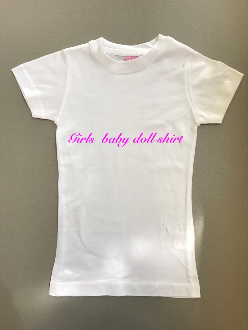 May include: White baby doll shirt with the text "Girls baby doll shirt" printed in pink.
