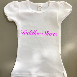 May include: White toddler shirt with a pink "Toddler Shirts" text on the front.
