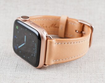 May include: A rose gold Apple Watch with a tan leather strap. The watch face shows the time and the word "Cloudy".