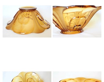 May include: A large amber glass bowl with a flower-shaped design. The bowl has a wide, shallow base and a flared rim. The bowl is made of clear glass with a slight amber tint.