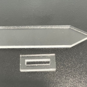 Puede incluir: Dos piezas de acrílico transparente, una con forma de flecha y la otra un rectángulo con una ranura cortada.