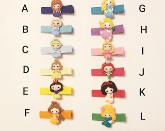 May include: Twelve colourful hair clips featuring different Disney princess characters. Each clip has a different colour ribbon and a different princess character. The characters include Elsa, Cinderella, Belle, Ariel, Snow White, Rapunzel, Aurora, Jasmine, Mulan, Pocahontas, Tiana, and Merida.