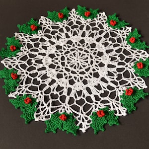 May include: White crocheted doily with a green and red holly border.