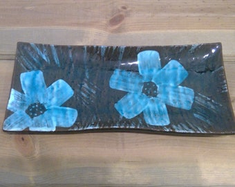 May include: A rectangular ceramic serving dish with a dark brown glaze and two blue floral designs.