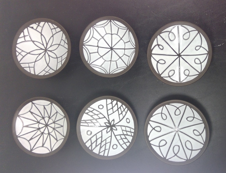 May include: Six white ceramic plates with black geometric designs. The plates are arranged in two rows of three, with the designs varying on each plate.