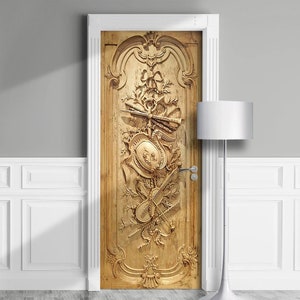 Può includere: Un adesivo per porte decorativo che presenta un design in legno intagliato con dettagli intricati. Il design include uno scudo, un violino e altri elementi decorativi. L'adesivo è di colore marrone chiaro e ha un'estetica vintage.