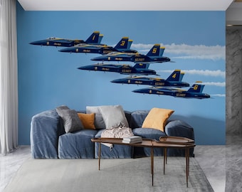 May include: A blue sofa with several pillows in shades of gray and orange sits in front of a wall mural. The mural depicts six blue and yellow U.S. Navy fighter jets in formation against a blue sky with white vapor trails.