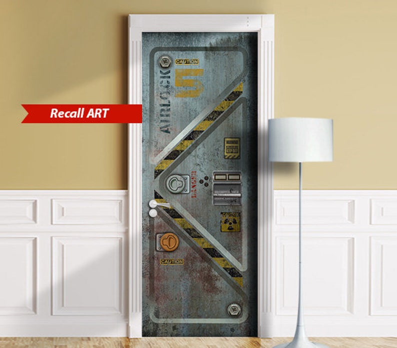 May include: A door decal featuring a weathered metal airlock design with yellow and black hazard stripes. The door has various warning labels and the text "AIRLOCK" and "CAUTION". The decal is framed in white and has the text "Recall ART" in a red banner.