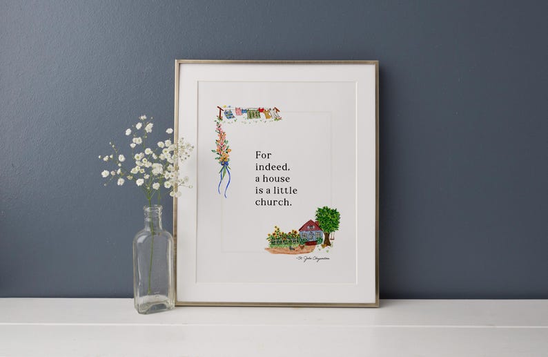 May include: Framed art print with a watercolour illustration. The artwork features a house, tree, and the text "For indeed, a house is a little church." A clear glass bottle with white flowers sits in front of the print.