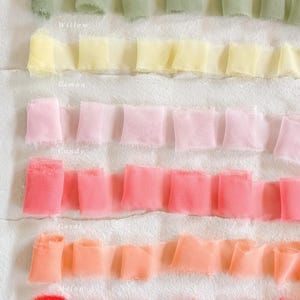 May include: Close-up of six rows of ruffled ribbon in various colours. The colours include willow, lemon, candy, coral, melon, and tangerine. The names of the colours are written below each row of ribbon.