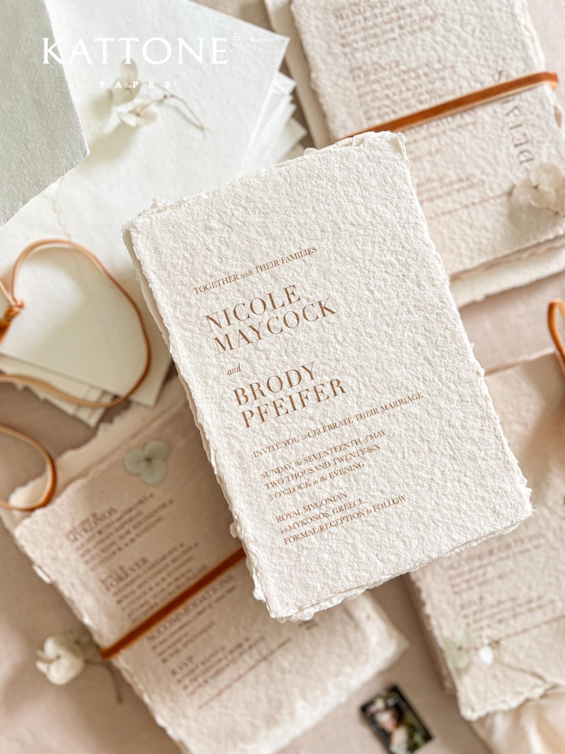 Luxury handmade paper wedding invitation suite styled with warm terracotta silk ribbon, textured cotton deckle edge paper cards and elegant minimalist typography design.