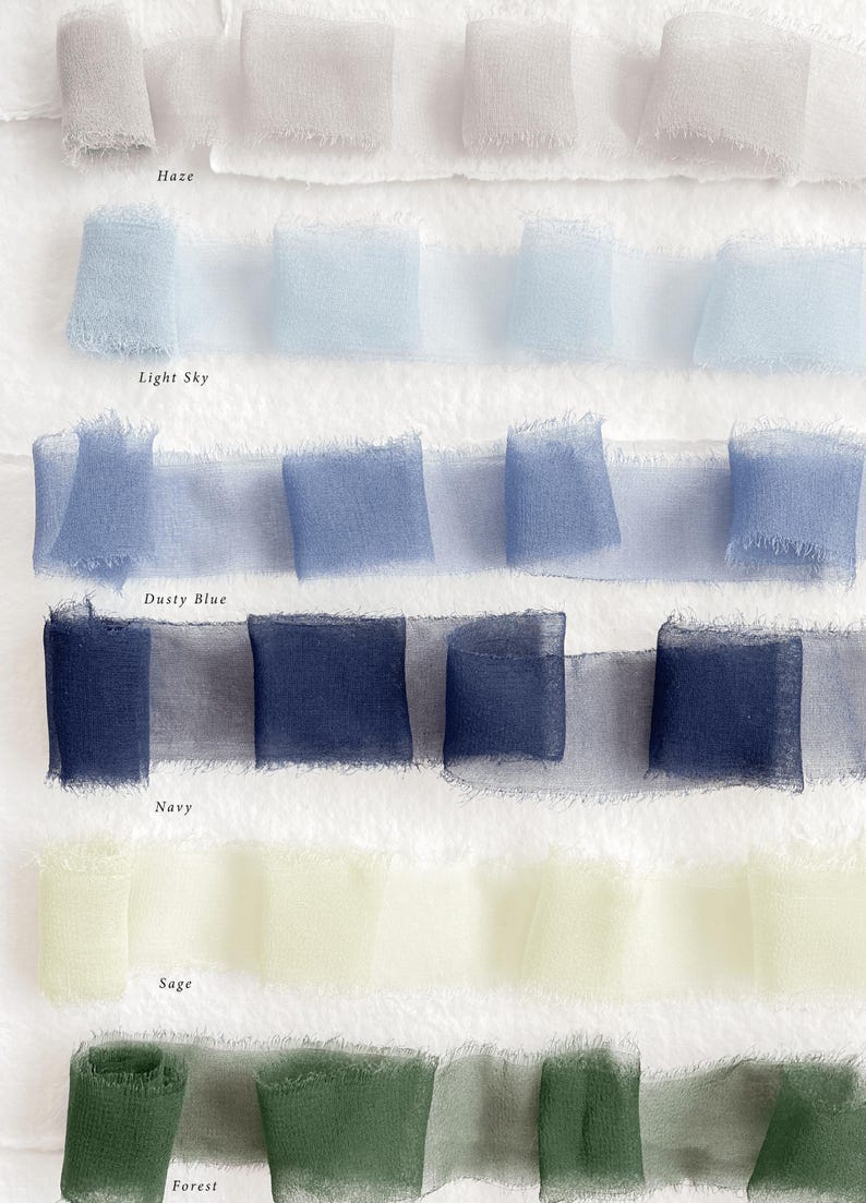 May include: Fabric ribbons in shades of Haze, Light Sky, Dusty Blue, Navy, Sage, and Forest. The ribbons are arranged in folded squares, with the colour names printed below each row. Ideal for craft projects.