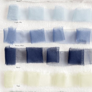 May include: Six rows of sheer ribbon in various shades of blue, green, and beige. The ribbon is arranged in rows with the names "Haze", "Light Sky", "Dusty Blue", "Navy", "Sage", and "Forest" written below each row.