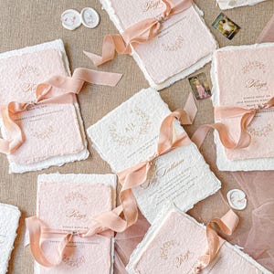 This exquisite handmade paper wedding invitations suite offers a blend of classic elegance and personalized artistry. Each bespoke invites set features a custom, hand-painted watercolor monogram of your initials, creating a unique and personal touch. The invitations are beautifully assembled with luxurious satin silk ribbons, adding a soft, opulent texture that your guests will adore.