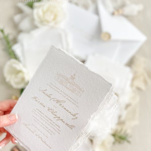May include: A white wedding invitation with gold lettering. The invitation announces the marriage of Sasha Hernandez and Warren Chiapparelli on Saturday, April 1st, 2023 at 2:00 PM at Parroquia Santiago Apostol in Tequila, Jalisco, Mexico. The invitation includes a small illustration of a church.
