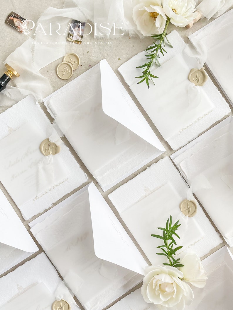 May include: White wedding invitations with white envelopes and wax seals. The invitations are decorated with sprigs of rosemary and white roses.