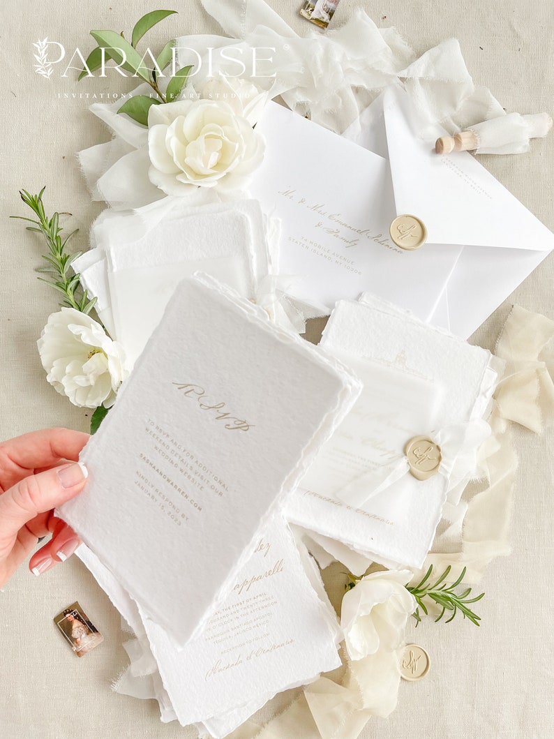 May include: White wedding invitation suite with gold calligraphy and wax seals. The invitation includes the couple's names, wedding date, and RSVP information. The invitation is on textured paper with a rustic, handmade look.