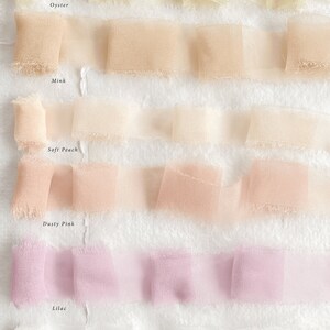 May include: Six samples of sheer ribbon in various shades of white, peach, pink, and lilac. The ribbon samples are labelled "Oyster", "Mink", "Soft Peach", "Dusty Pink", "Lilac", and "White".