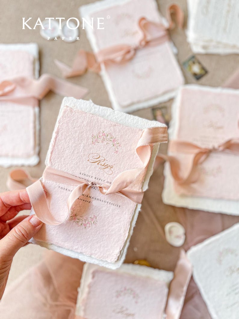 This exquisite handmade paper wedding invitations suite offers a blend of classic elegance and personalized artistry. Each bespoke invites set features a custom, hand-painted watercolor monogram of your initials, creating a unique and personal touch. The invitations are beautifully assembled with luxurious satin silk ribbons, adding a soft, opulent texture that your guests will adore.
