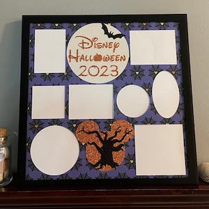 May include: A black picture frame with a purple background and a white circle with the text "Disney Halloween 2023" in orange and black lettering. The frame has multiple white picture openings in various shapes and sizes.