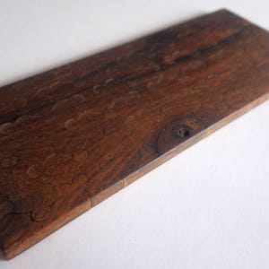 May include: A rectangular wooden puzzle with a rich, dark brown color and visible wood grain. The puzzle pieces are cut in a unique, organic shape. The wood has a smooth, polished finish, and the puzzle is set against a white background.