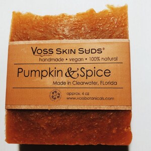 May include: A bar of brown soap with a label that reads "VOSS SKIN SUDS handmade vegan 100% natural Pumpkin & Spice Made in Clearwater, Florida approx. 4 oz www.vossbotanicals.com"