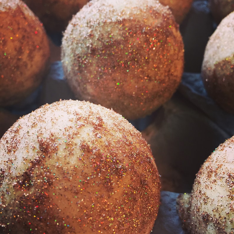 May include: Close-up of round, white ornaments covered in brown glitter. The ornaments have a subtle shimmer and sparkle.