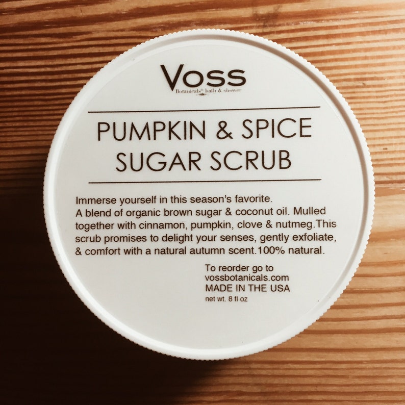 May include: White jar with a black label that reads "Voss Botanicals Bath & Shower Pumpkin & Spice Sugar Scrub". The label also includes the text "Immerse yourself in this season's favorite. A blend of organic brown sugar & coconut oil. Mulled together with cinnamon, pumpkin, clove & nutmeg. This scrub promises to delight your senses, gently exfoliate, & comfort with a natural autumn scent. 100% natural. To reorder go to vossbotanicals.com MADE IN THE USA net wt. 8 fl oz".