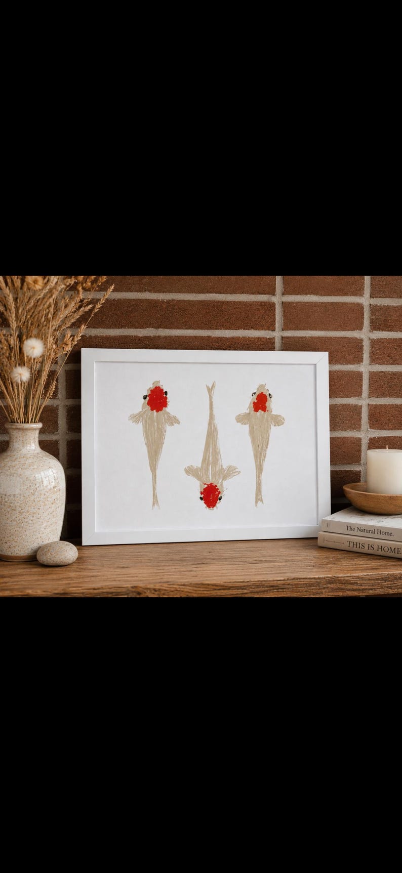 May include: A rectangular white frame containing a print of three koi fish. The fish are depicted in a light beige color with distinct red markings on their heads, arranged vertically against a plain white background within the frame.
