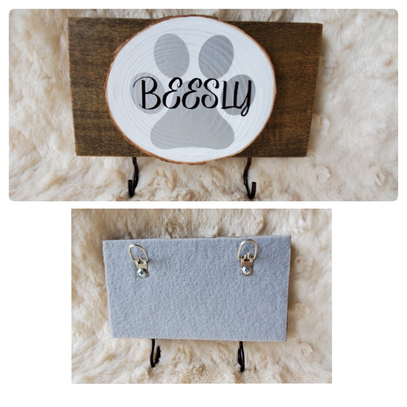 May include: Wooden key holder with a gray paw print and the name "Beesly" painted on a white wood slice. The key holder has two black metal hooks.