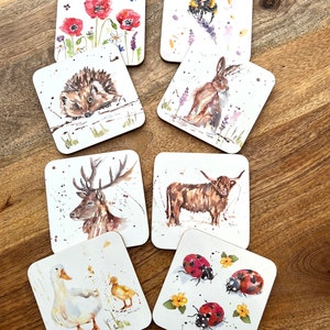 May include: Set of eight square coasters featuring watercolor illustrations of various animals and nature scenes. The coasters depict a hedgehog, a deer, a cow, a rabbit, a bee, ladybugs, a goose and a duckling, and poppies.