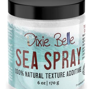 May include: A cylindrical container of Dixie Belle Sea Spray 100% natural texture additive with a black lid. The label features a light blue ocean wave graphic, dark red text reading SEA SPRAY, and indicates a net weight of 6 oz | 170 g.