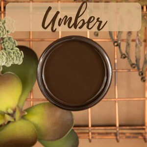 Könnte beinhalten: Ein kleines Glas mit dunkelbrauner Farbe, auf dem das Wort "Umber" in weiß auf braunem Hintergrund steht.