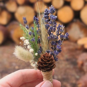 May include: A small bouquet of dried flowers, including lavender, wheat, and a pine cone, tied with twine.
