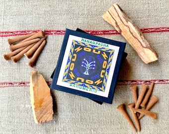 May include: An assortment of incense sticks, wood pieces, and a box with the text "HANAQPACHA SAHUMERIO" in a square design. The items are arranged on a textured, neutral-toned surface with red stripes.