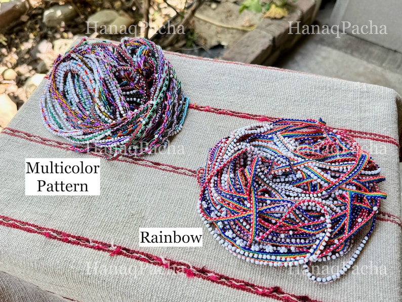 K&ouml;nnte beinhalten: Zwei Spulen mit bunten Perlenf&auml;den. Die Spule links hat ein mehrfarbiges Muster. Die Spule rechts hat ein Regenbogenmuster. Beide Spulen liegen auf einem wei&szlig;-rot gestreiften Stoff.