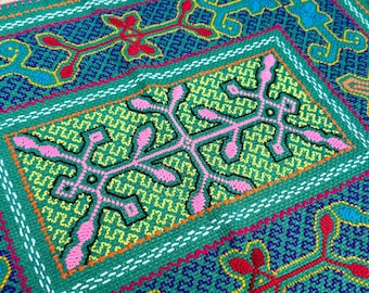 May include: A textile piece featuring intricate embroidery with a central rectangular panel in lime green, decorated with pink symmetrical floral-like motifs. The surrounding border is teal with blue, red, and orange geometric patterns.