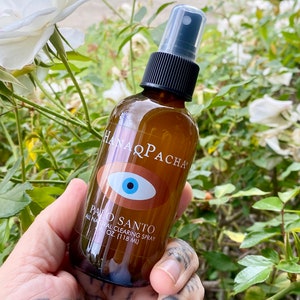 Peut inclure: Une bouteille en verre brun avec un vaporisateur noir et une &eacute;tiquette blanche qui indique "Hanaqpacha Palo Santo All Natural Clearing Spray 4 oz (118 ml)". L'&eacute;tiquette pr&eacute;sente &eacute;galement un &oelig;il bleu avec une pupille blanche et un iris brun.