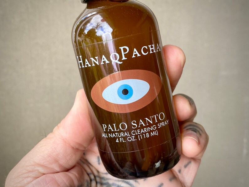 Peut inclure: Une bouteille en verre brun avec une &eacute;tiquette blanche qui dit "HANAQ PACHA" et "PALO SANTO ALL NATURAL CLEARING SPRAY 4 FL. OZ. (118 ML)". L'&eacute;tiquette pr&eacute;sente &eacute;galement un &oelig;il bleu avec une pupille noire &agrave; l'int&eacute;rieur d'un ovale brun.