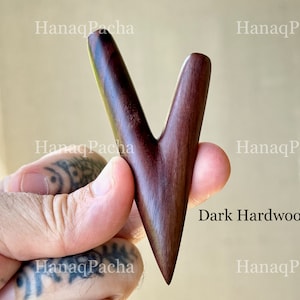 May include: A V-shaped dark hardwood tool with a smooth, polished finish and a pointed base. The object features a bifurcated top section with two rounded prongs. The text "HanaqPacha" is visible in the background, and "Dark Hardwood" is printed.