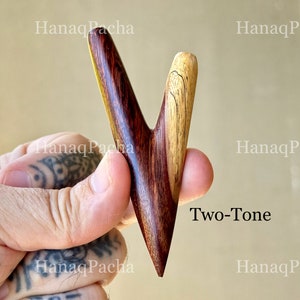 May include: A V-shaped wooden hair accessory featuring a two-tone design with a dark reddish-brown grain on the left side and a lighter tan grain on the right side. The text HanaqPacha and Two-Tone are visible on the image surface.