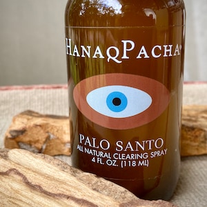 Peut inclure: Une bouteille en verre brun avec une &eacute;tiquette blanche qui indique "HANAPACHA" et "PALO SANTO ALL NATURAL CLEARING SPRAY 4 FL. OZ. (118 ML)". L'&eacute;tiquette pr&eacute;sente &eacute;galement un &oelig;il brun avec un iris bleu et une pupille noire.