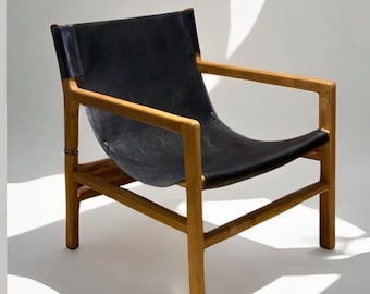 May include: A black leather chair with a wooden frame. The chair has a simple design with a wide, curved seat and a low back.