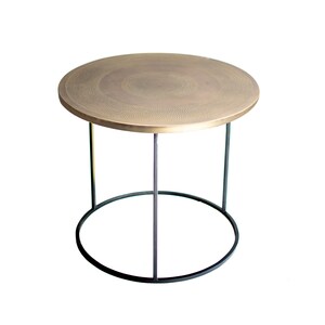 May include: A round brass side table with a hammered finish and a black metal frame.