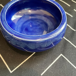 May include: A small, blue ceramic bowl with white marbling. The bowl is empty and has a smooth, glossy finish.