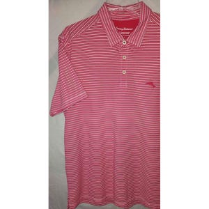 Puede incluir: Polo de manga corta a rayas rosas y blancas. La camisa tiene cuello, tapeta de tres botones y bolsillo en el pecho. La marca "Tommy Bahama" es visible en el cuello. Confeccionada en tejido ligero.