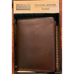 May include: A dark brown genuine leather trifold wallet inside a rectangular box. The packaging features the text Basic Editions and Genuine Leather Trifold. The wallet has a smooth, solid-colored surface with visible stitching along the edges.