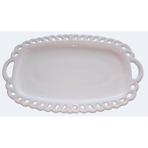May include: A white oval ceramic tray featuring a smooth, flat center surface and a decorative, openwork lattice border. The tray includes two integrated handles on the left and right sides, forming a continuous, symmetrical, and glossy white design.
